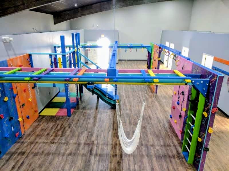 Overhead view of a commercial sensory gym installation with climbing walls, monkey bar beams, and hammock
