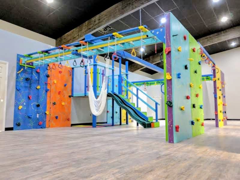 Spectrum Sensory Gyms commercial build with splatter climbing walls, monkey bar grid, hammock swing, and slide