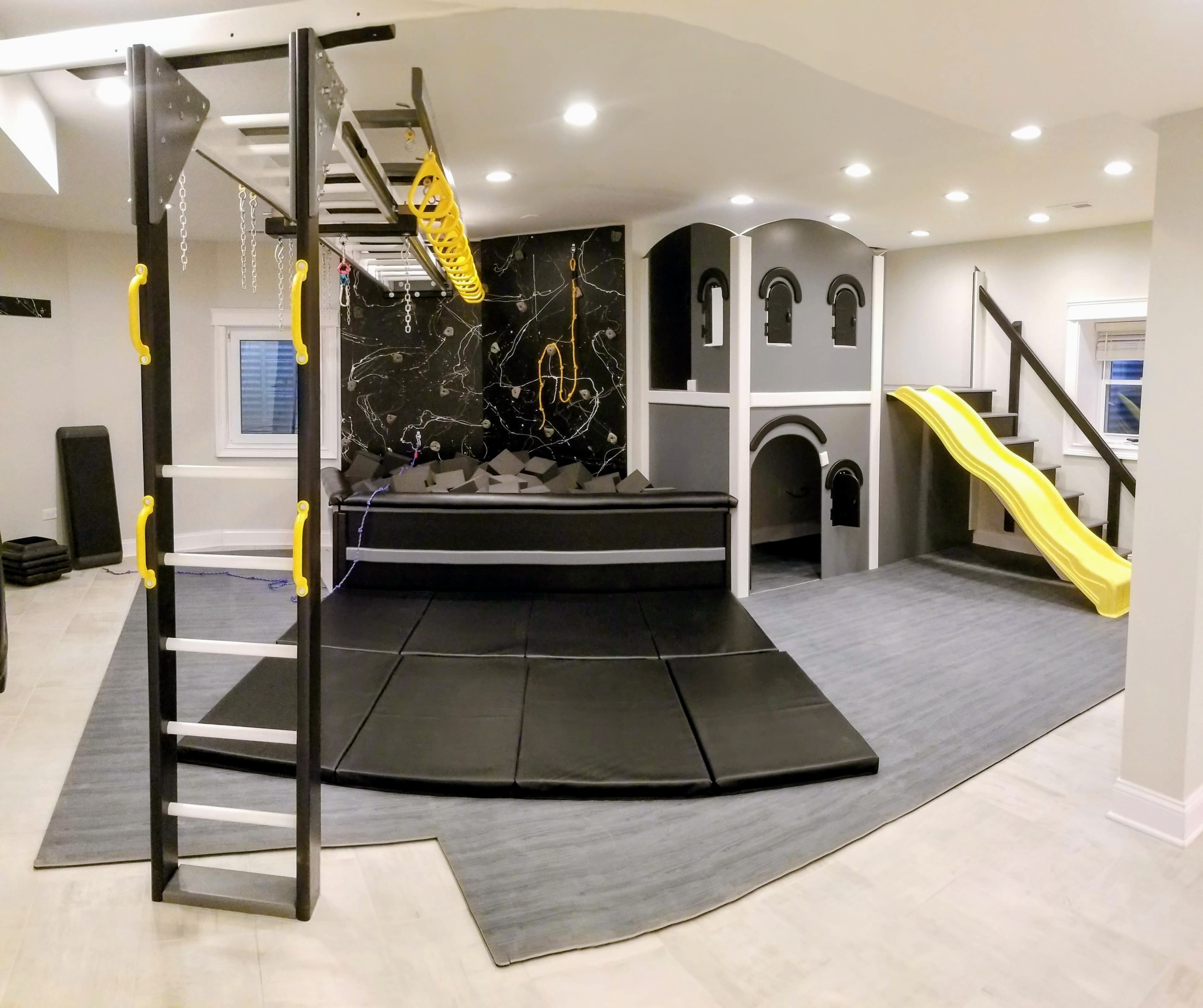 Premium residential gym with dark marble theme, foam pit, yellow slide, and castle structure